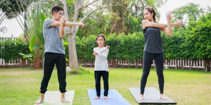 Family performing outdoor tai chi exercise together.