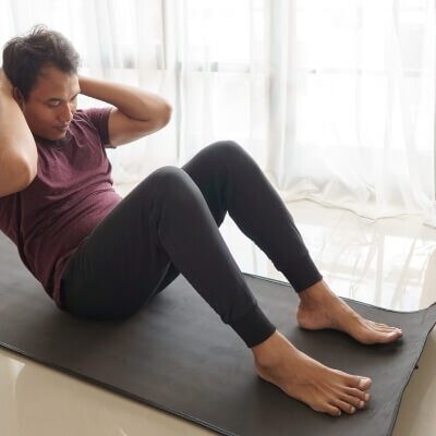 Man in a seated position doing abdominal crunches on a yoga mat.