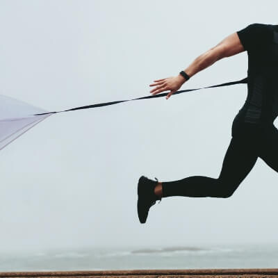 Man in black running with parachute
