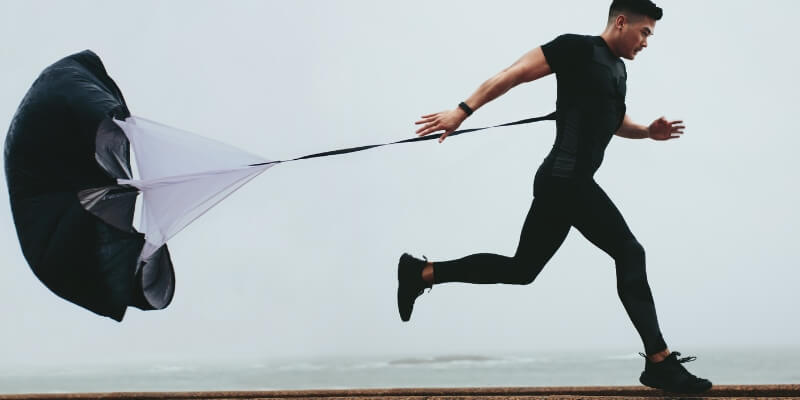 Man in black running with parachute