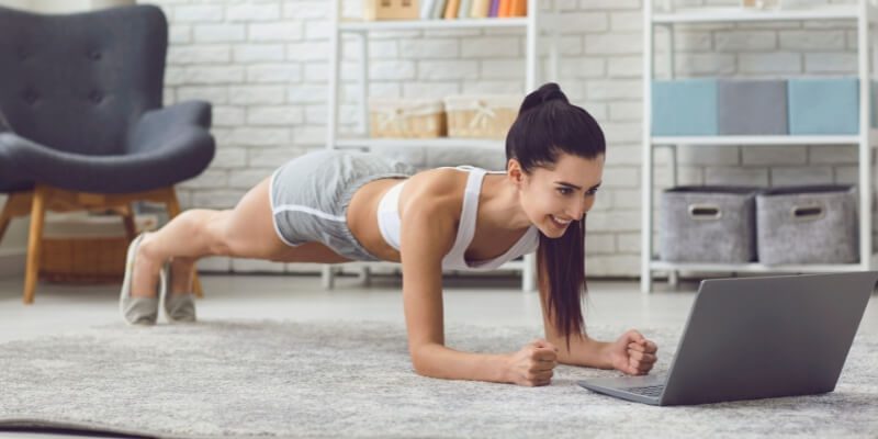 Woman doing a plank while watching an online workout class.