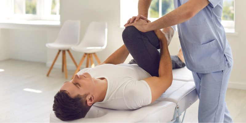 Man on bed raising knee to his chin